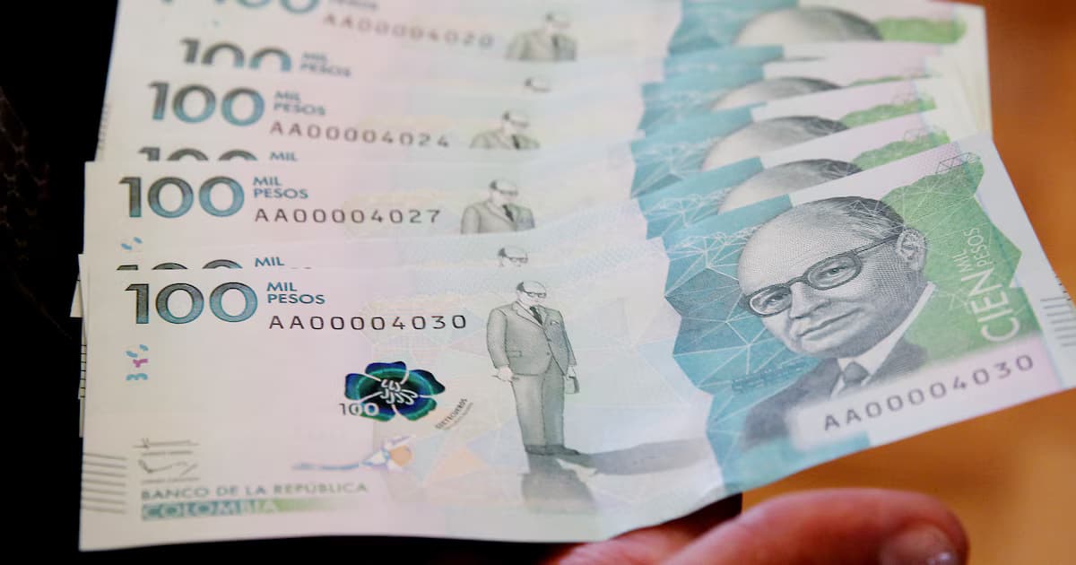 Billetes de cien mil pesos colombianos sostenidos en abanico