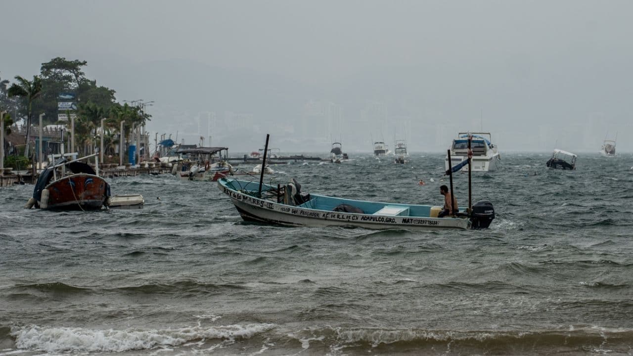 Lanchas de pescadores sacudidas por el oleaje bajo la lluvia en la bahía de Acapulco por el huracán Polo