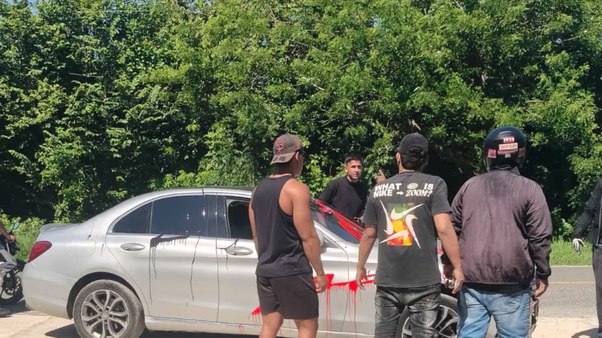 Un carro plateado con pintura roja, rodeado de personas frente a la sede de Junior en Sabanilla