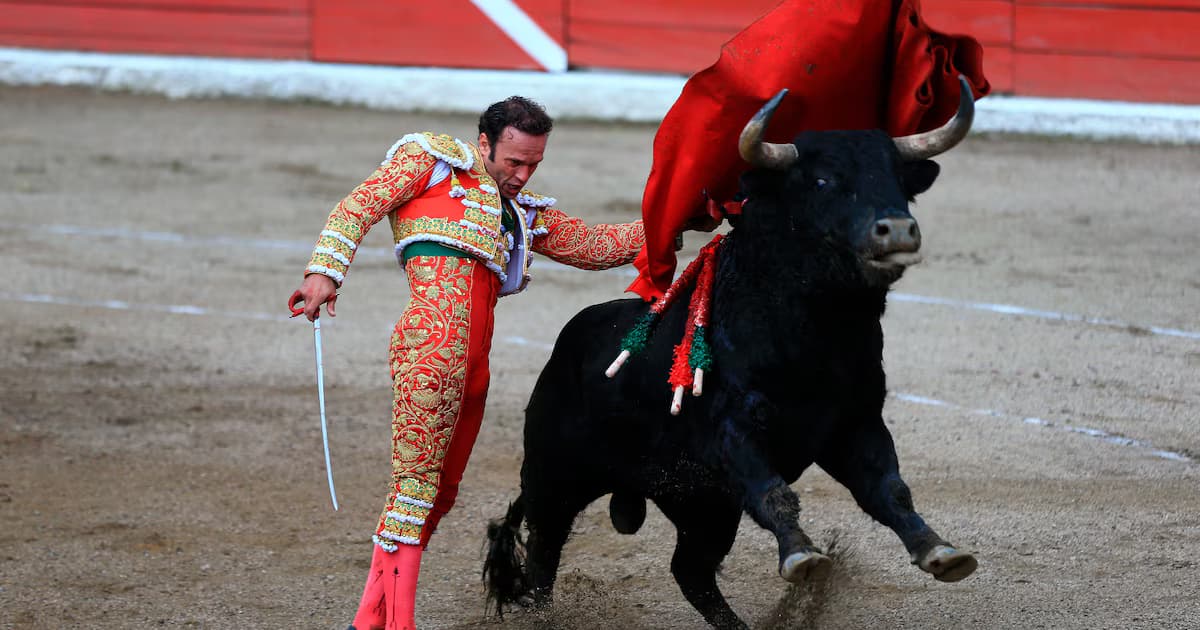 Un torero da un pase con la muleta a un toro en una plaza