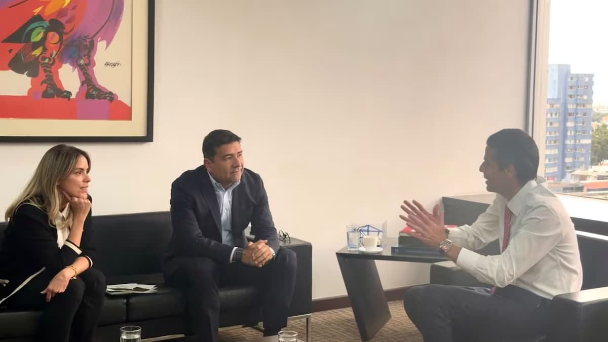 Tres personas conversan sentadas en los sofás de una oficina