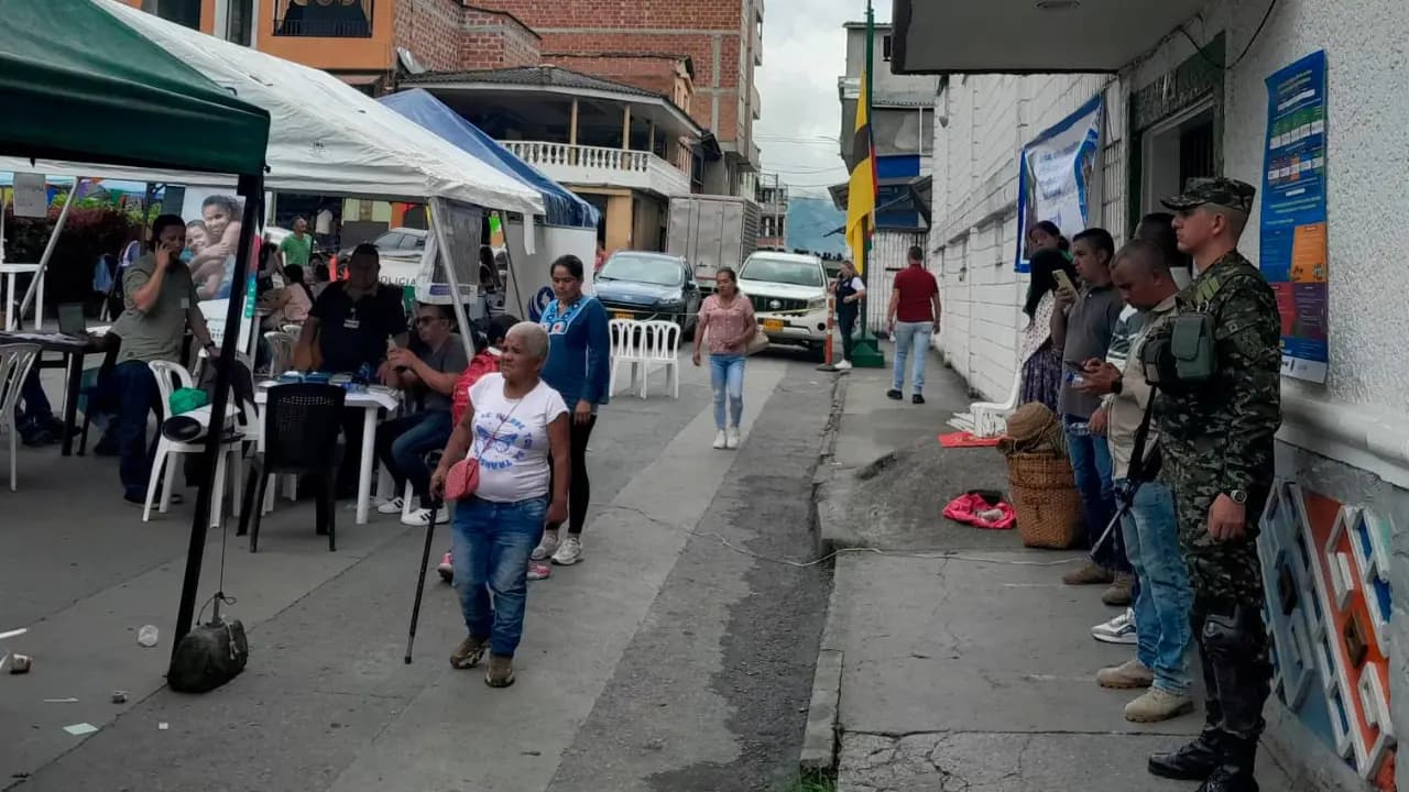 Familias desplazadas esperan bajo carpas en una calle de Ituango, con presencia de policías y militares