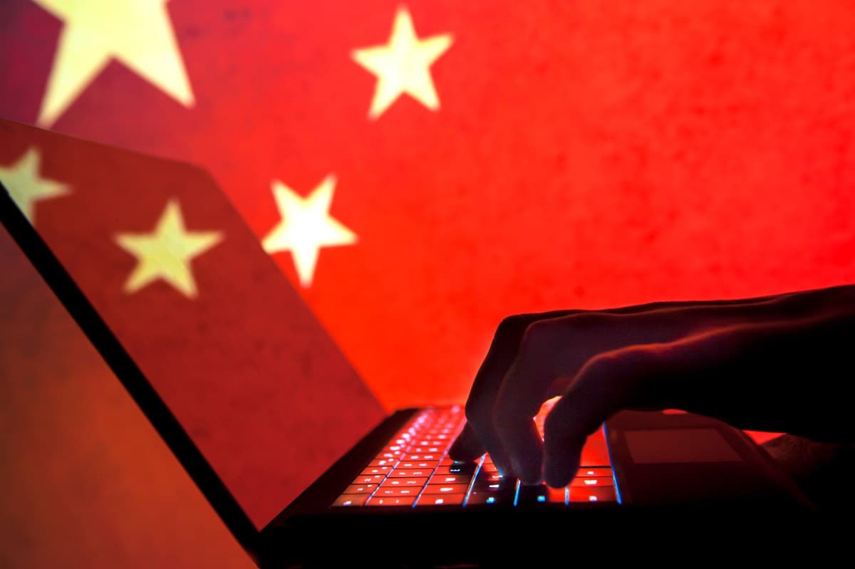Persona frente a un portátil con la bandera de China proyectada al fondo
