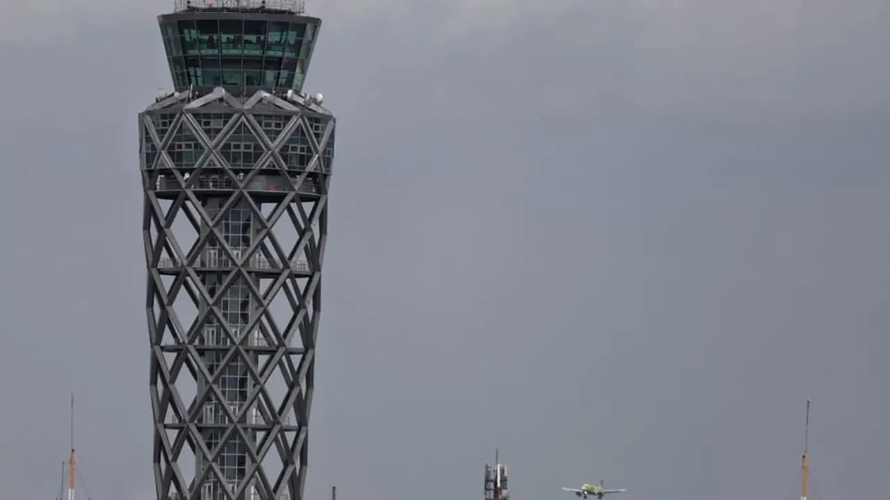 Torre de control del aeropuerto El Dorado, en Bogotá, con un avión aproximando al fondo