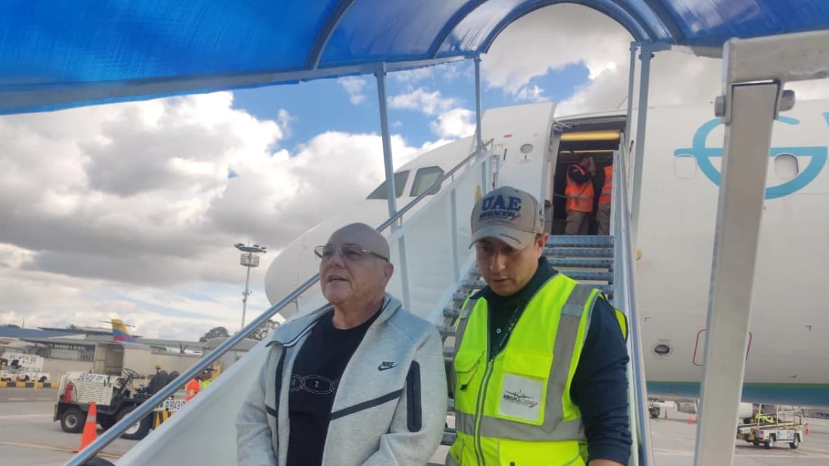 Eugenio Montoya al pie de la escalerilla de un avión, acompañado por un funcionario de Migración Colombia