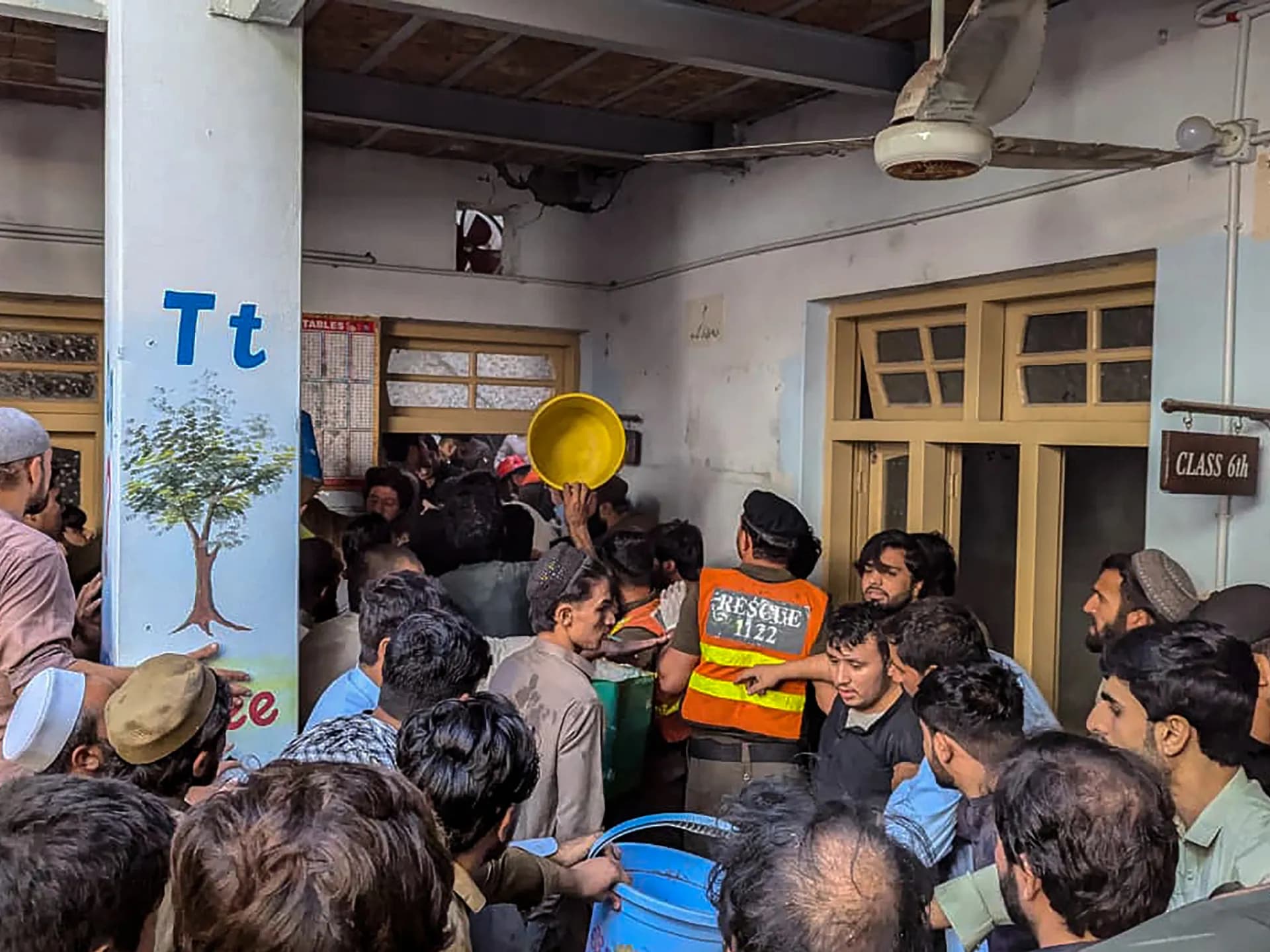 Rescatistas y vecinos se agolpan en el pasillo de la escuela de Peshawar donde se derrumbó el techo