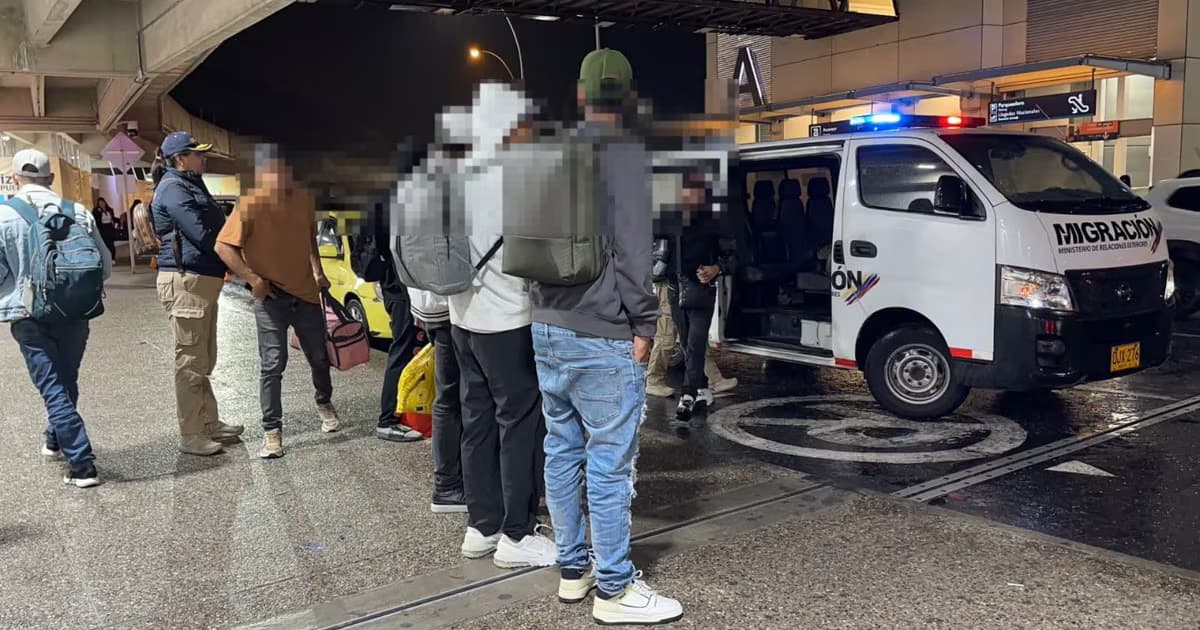 Ciudadanos extranjeros junto a una camioneta de Migración Colombia en un aeropuerto durante un procedimiento de expulsión
