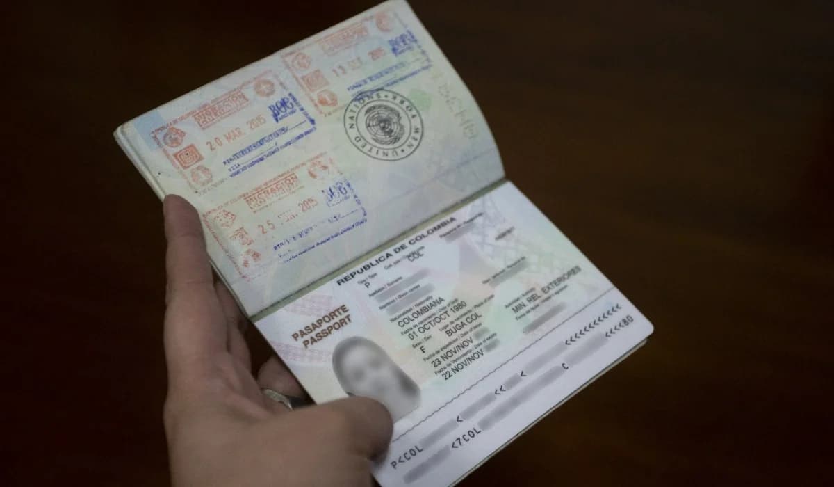 Una persona sostiene un pasaporte colombiano abierto en la página de datos