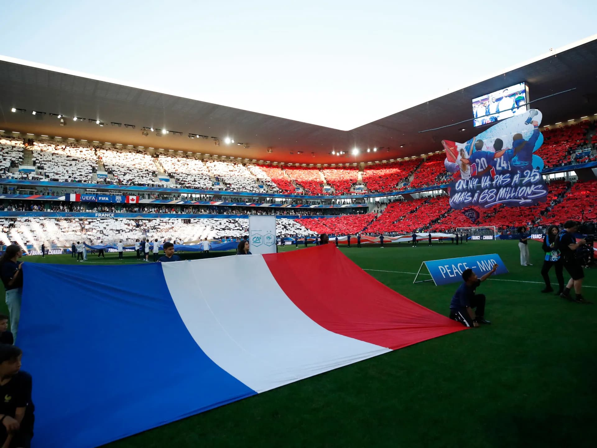 Una gran bandera de Francia sobre el césped del estadio de Burdeos, con las tribunas llenas antes de un partido amistoso