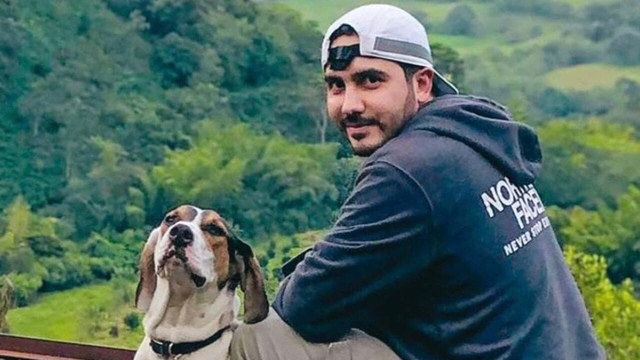 Andrés Camilo Peláez Yepes, de gorra blanca y buzo oscuro, junto a un perro en una zona montañosa