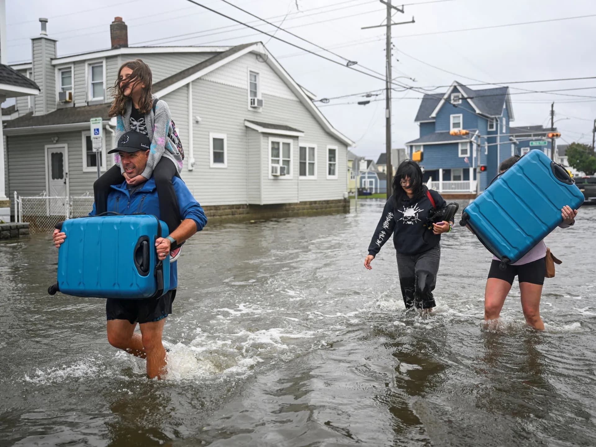 Una familia camina con sus pertenencias por una calle inundada en Wildwood, Nueva Jersey