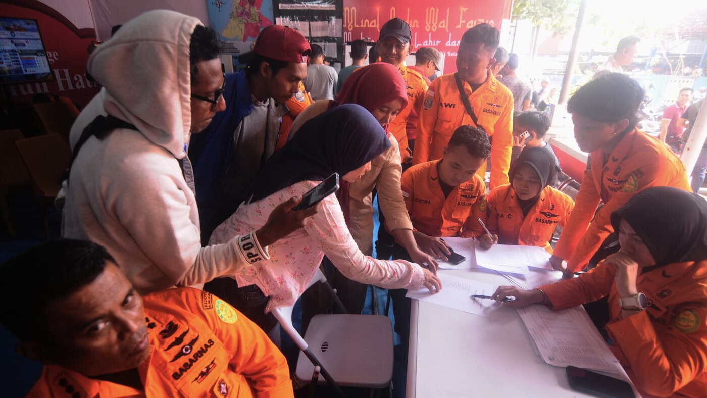 Familiares revisan la lista de pasajeros junto a rescatistas en el centro de mando de Banjarmasin, Indonesia