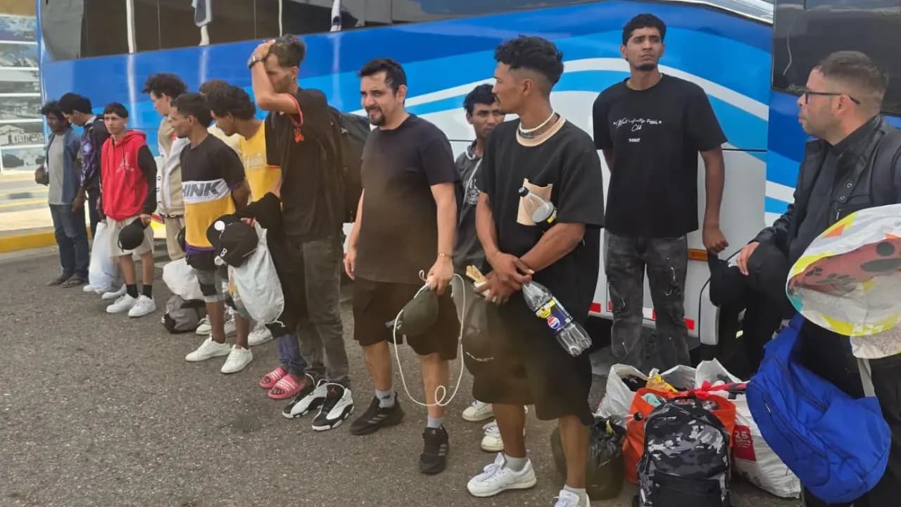 Grupo de ciudadanos venezolanos expulsados, junto a un bus antes de su traslado