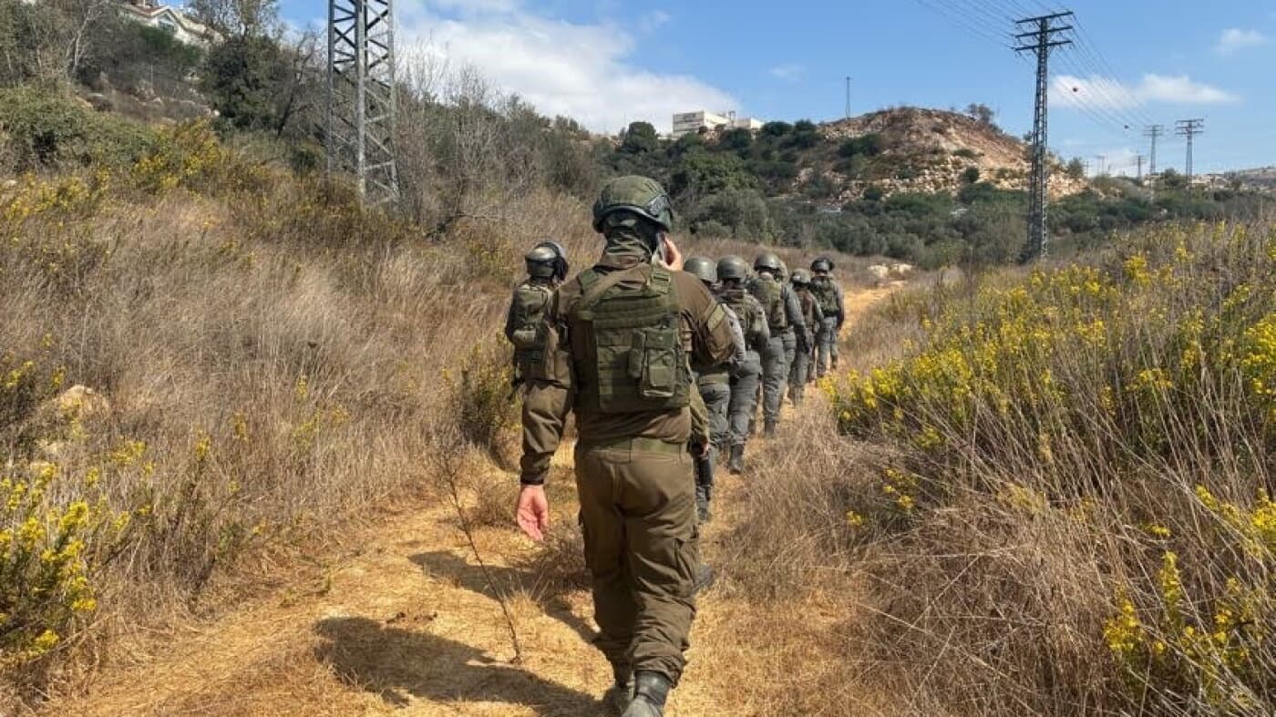 Fuerzas de seguridad israelíes caminan en fila por un sendero junto a un olivar cerca del asentamiento de Beitar Illit, en Cisjordania
