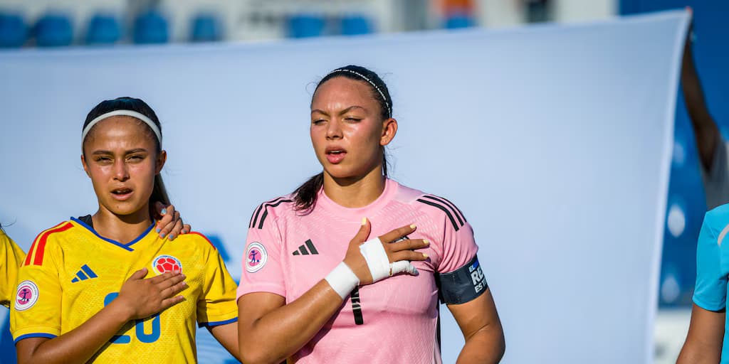 Una jugadora de la selección Colombia Sub-20 con camiseta amarilla y una arquera de uniforme rosado durante los himnos en el Mundial Femenino Sub-20