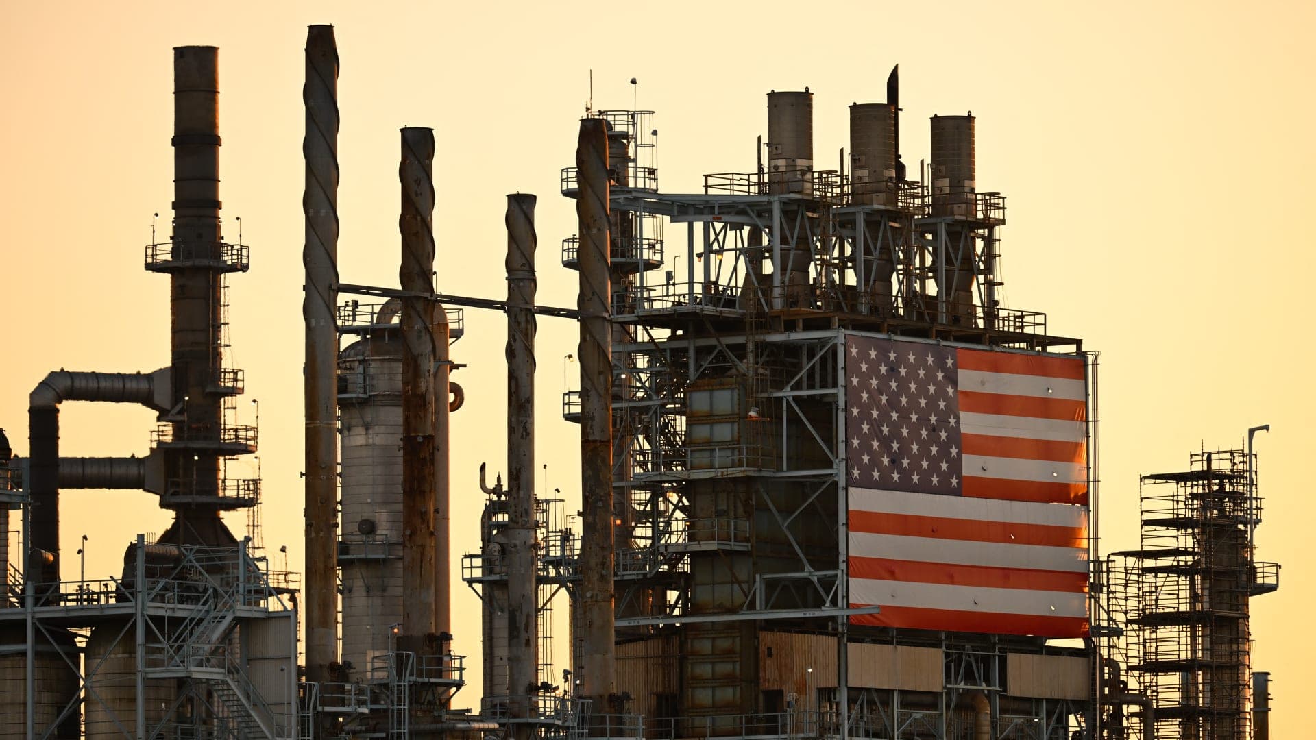 Refinería de petróleo en Estados Unidos con una gran bandera estadounidense al atardecer