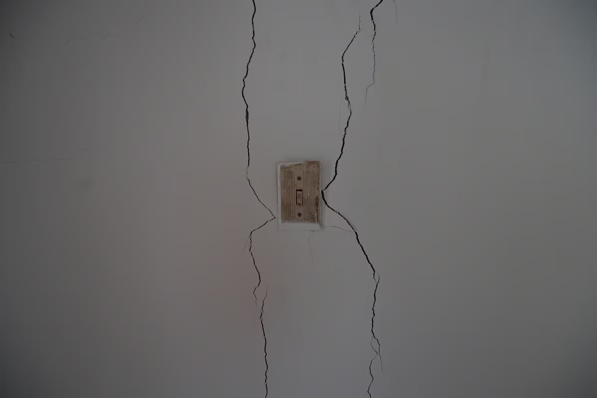 Dos grietas verticales recorren la pared de una vivienda a lado y lado de un interruptor de luz