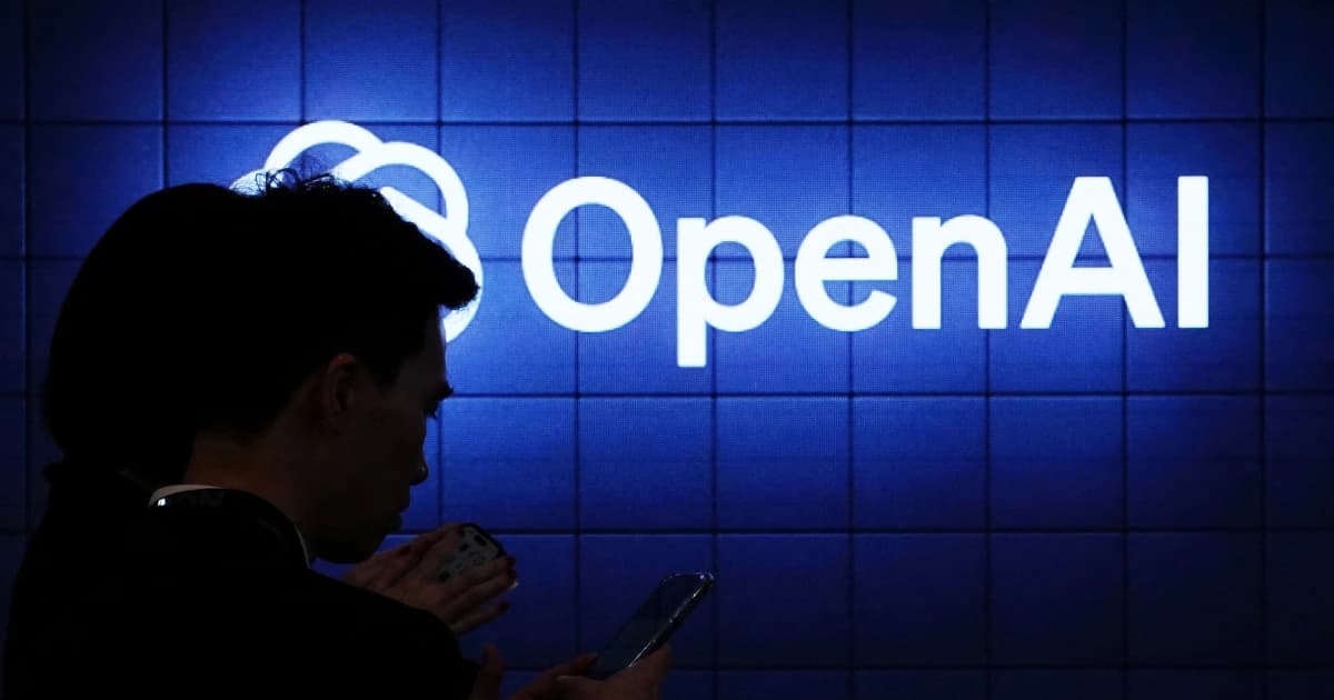 Un hombre mira su celular frente a un letrero iluminado con el logo de OpenAI