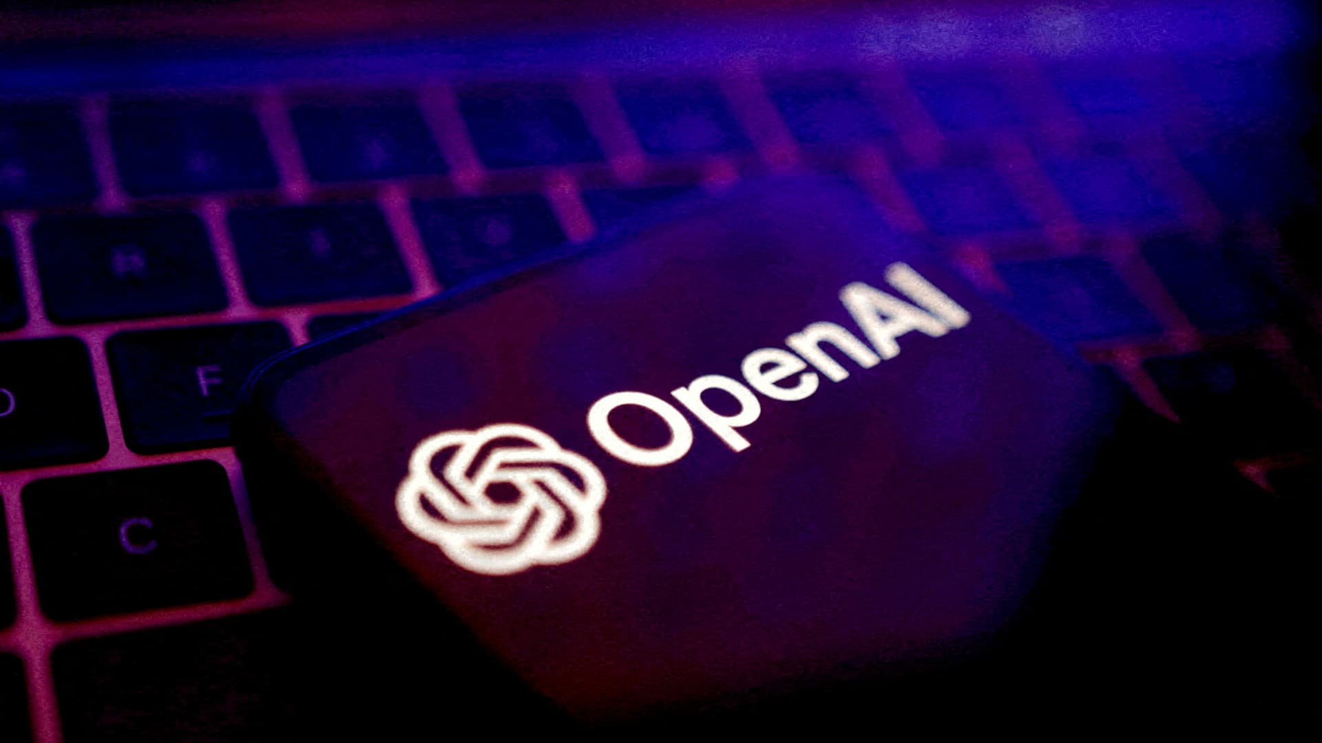 El logotipo de OpenAI en la pantalla de un teléfono sobre el teclado de un computador