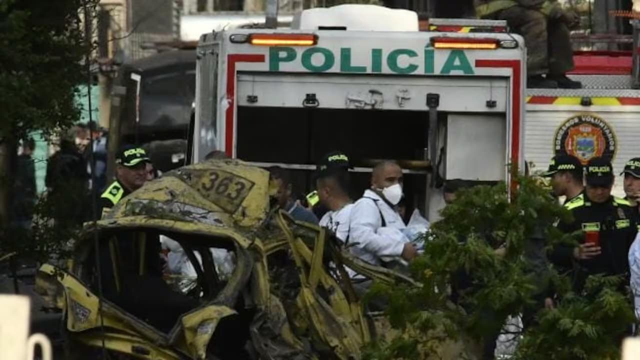 Policías y peritos junto a un taxi destruido tras el atentado cerca de la Base Aérea Marco Fidel Suárez, en Cali