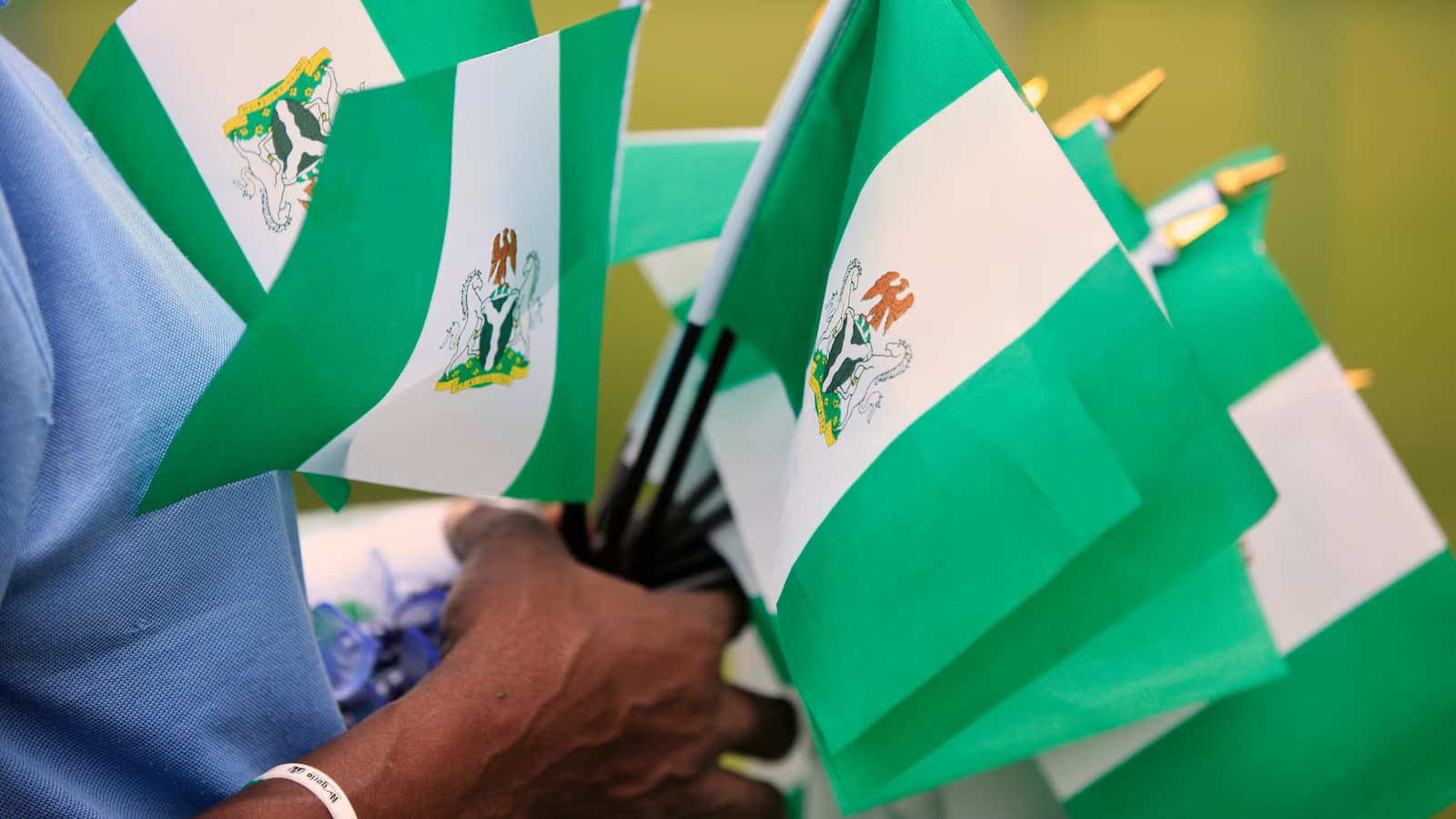 Un hombre sostiene un manojo de banderas de Nigeria