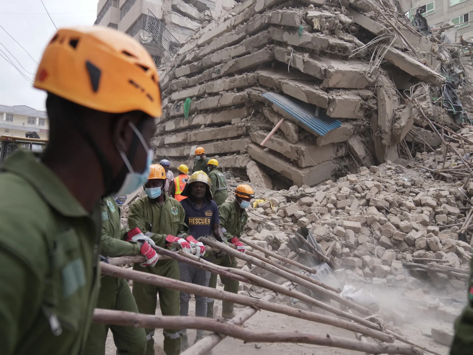 Rescatistas con cascos tiran de palos de madera frente a los restos del edificio derrumbado en Eastleigh, Nairobi