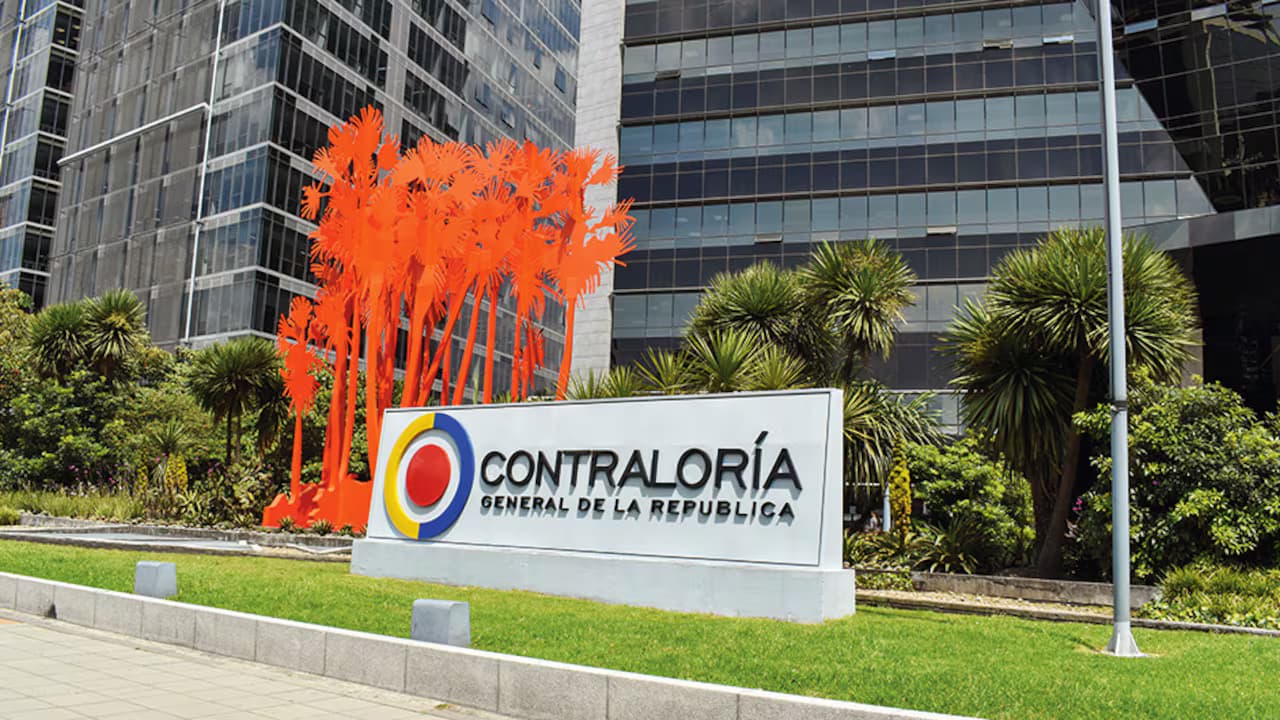 Fachada de vidrio del edificio de la Contraloría General de la República en Bogotá con su valla y una escultura naranja al frente