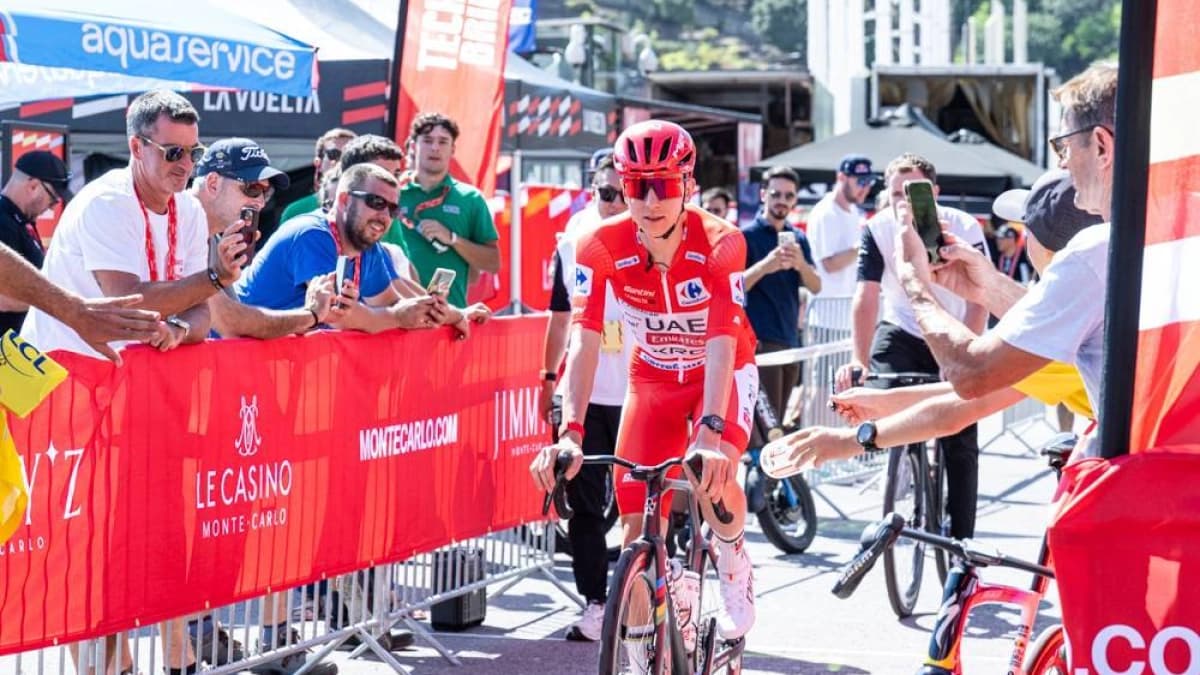 Tadej Pogacar, con el maillot rojo de líder, avanza en bicicleta entre el público en la zona de salida