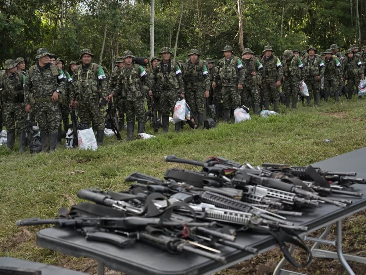 Excombatientes de la Coordinadora Nacional Ejército Bolivariano en formación junto a una mesa con armas