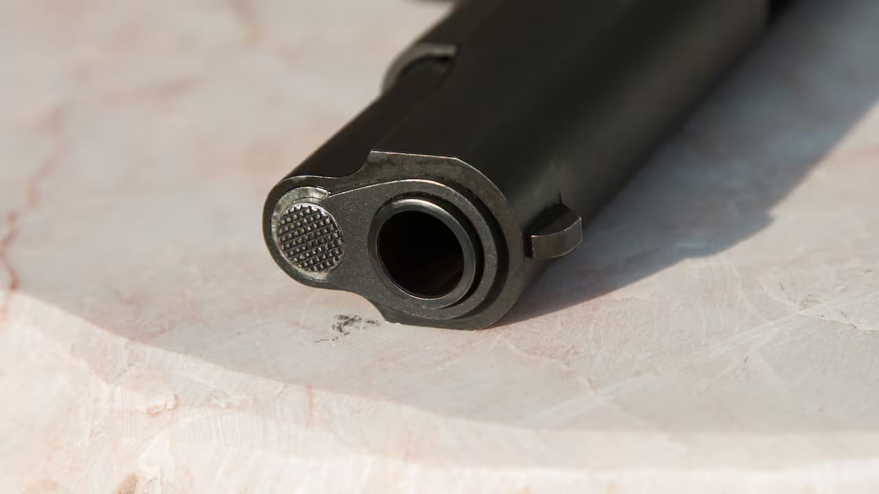 Primer plano del cañón de una pistola sobre una superficie de piedra clara
