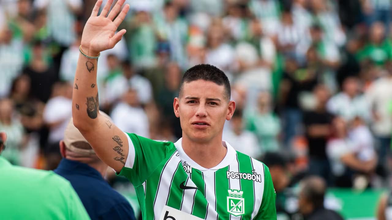James Rodríguez, con la camiseta verde y blanca de Atlético Nacional, saluda con la mano en alto frente a la tribuna