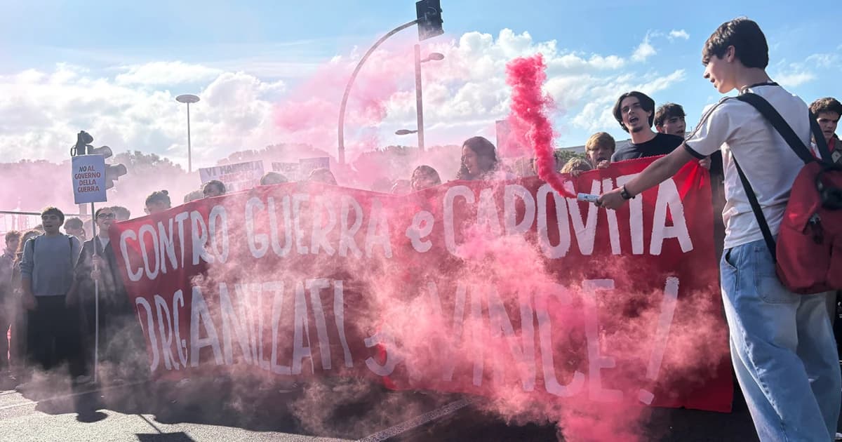 Estudiantes con bengalas de humo y una pancarta contra la guerra y el costo de vida durante la huelga general en Italia