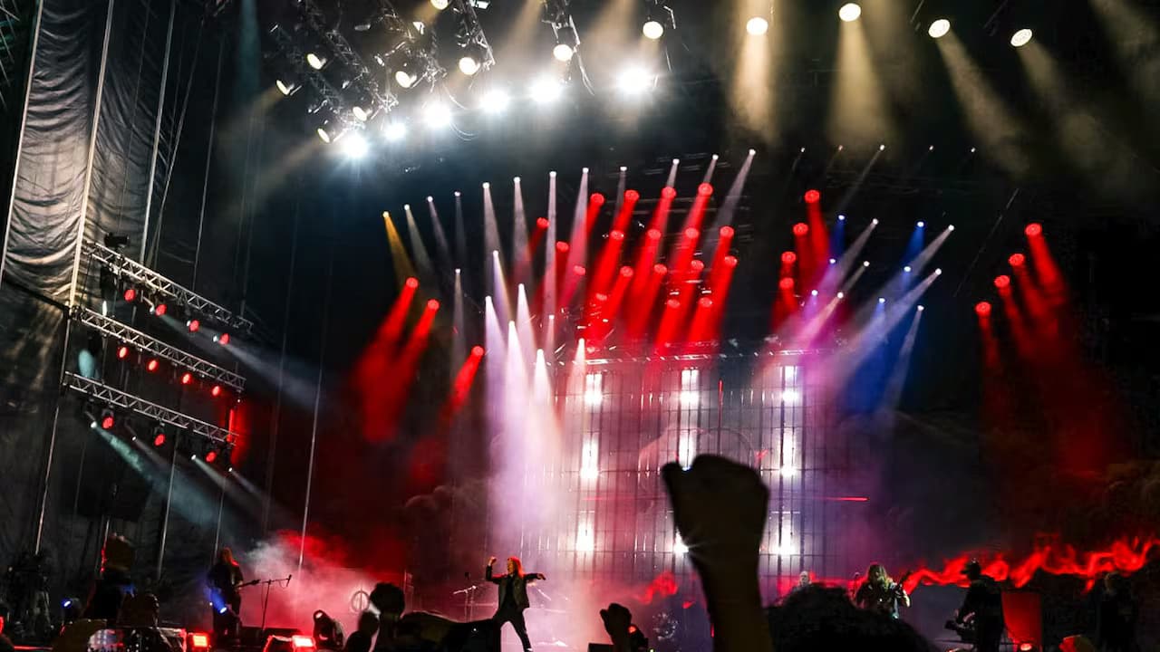 Público con el puño en alto frente a una tarima iluminada de Rock al Parque en el parque Simón Bolívar