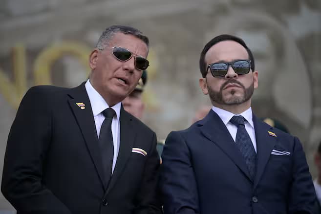 Dos altos funcionarios de traje y gafas oscuras durante un acto de la Fuerza Pública