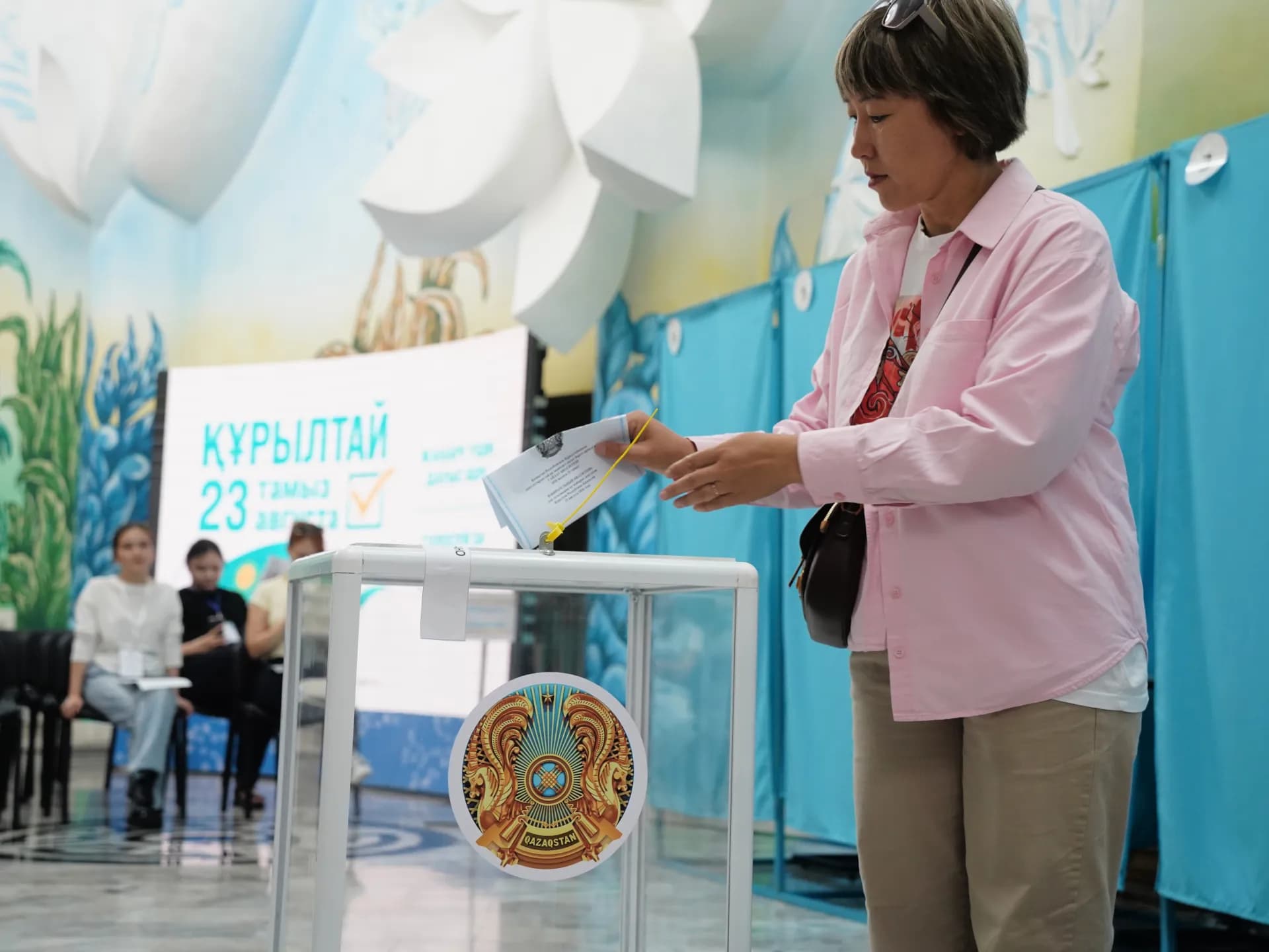 Una mujer deposita su voto en una urna transparente en un colegio electoral de Kazajistán