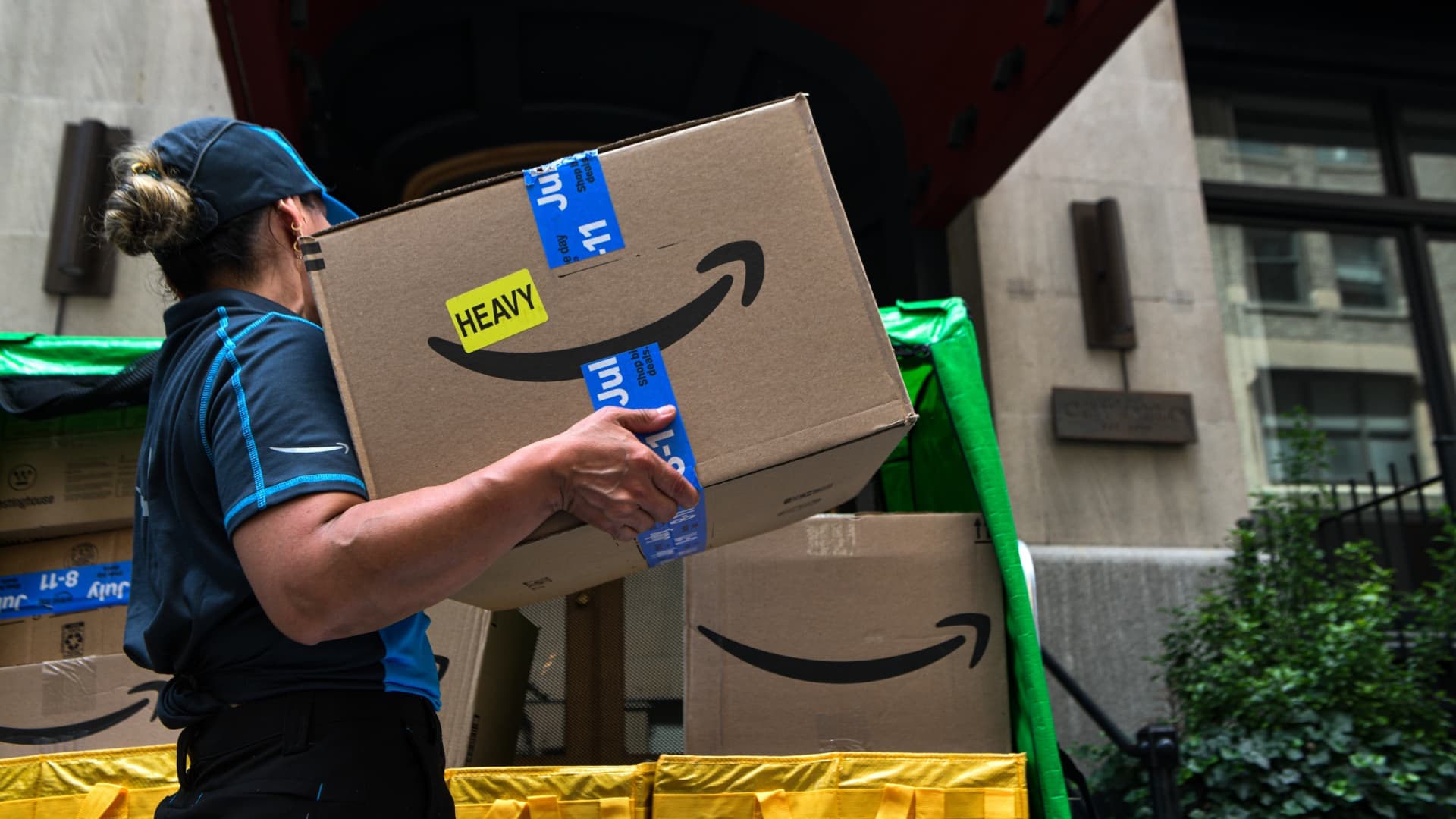 Una trabajadora de reparto de Amazon carga una caja con el logotipo de la compañía en una calle