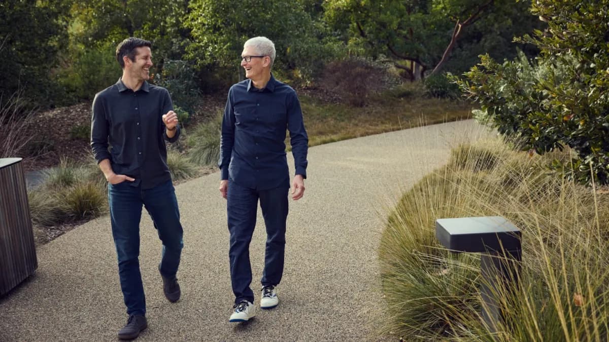 John Ternus y Tim Cook caminan y conversan por un sendero rodeado de vegetación en la sede de Apple