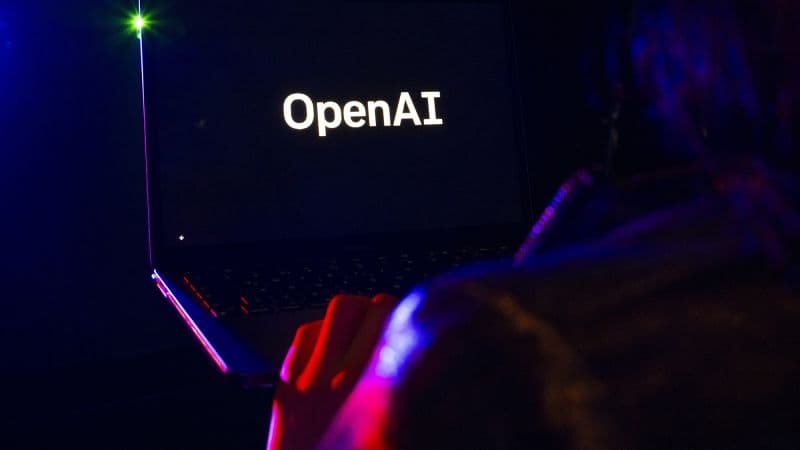 Una mujer mira la pantalla de un portátil con el logo de OpenAI