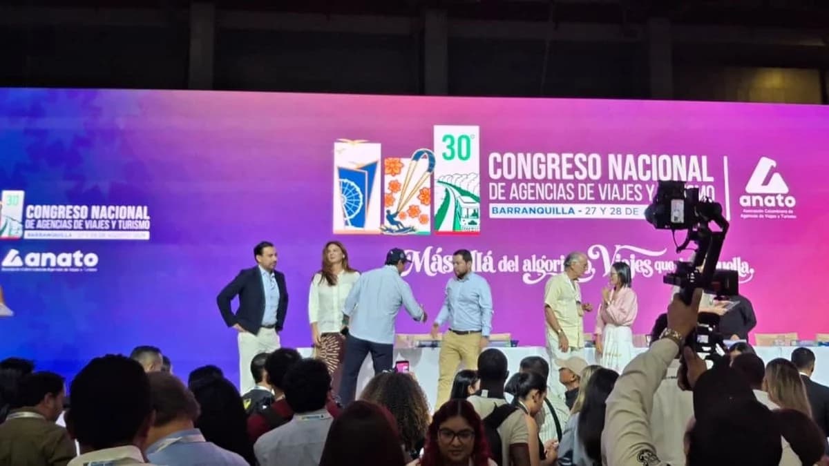 Escenario del Congreso Nacional de Agencias de Viajes y Turismo de Anato en Barranquilla, con varias personas de pie ante una pantalla y el público de espaldas