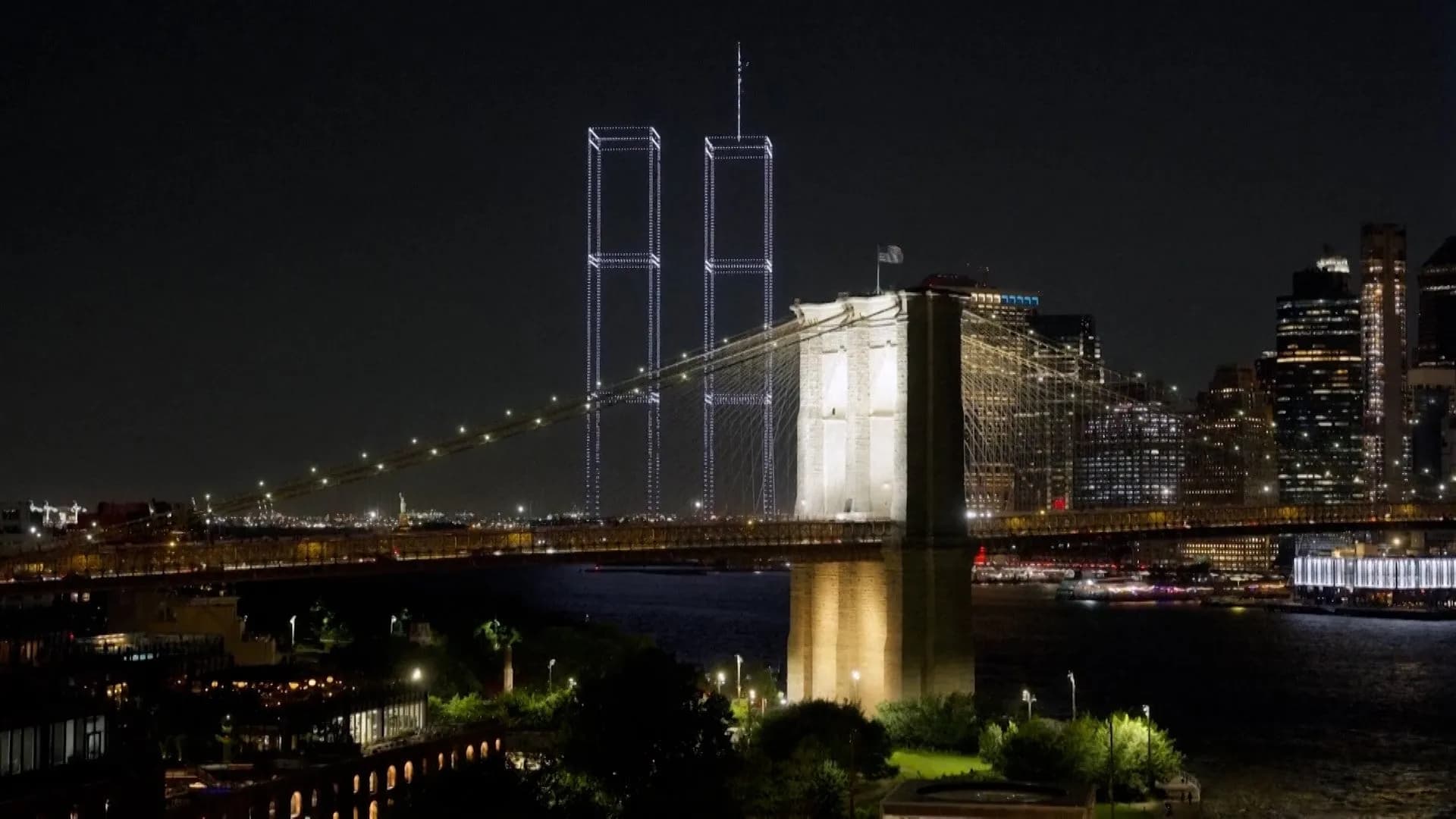 Drones iluminados dibujan la silueta de las Torres Gemelas sobre el puente de Brooklyn de noche
