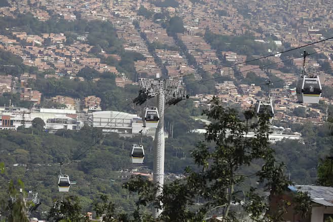 Cabinas del metrocable de Medellín sobre las laderas del oriente de la ciudad, con viviendas de ladrillo al fondo