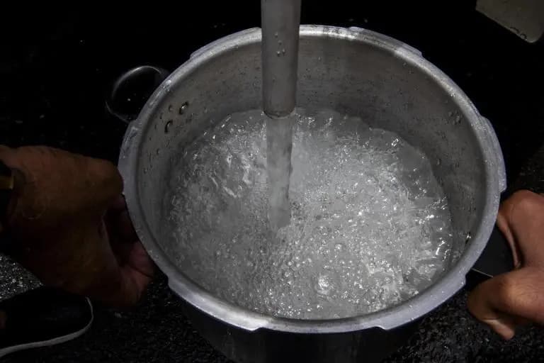 Una persona llena de agua una olla bajo un chorro