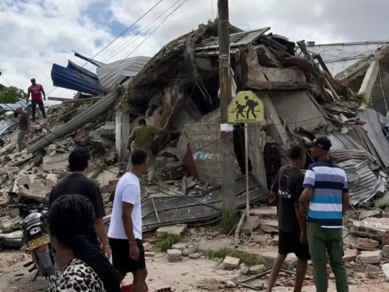 Un grupo de habitantes observa el montón de escombros de una edificación derrumbada por el terremoto en una calle del Chocó, con láminas de zinc retorcidas y placas de concreto partidas