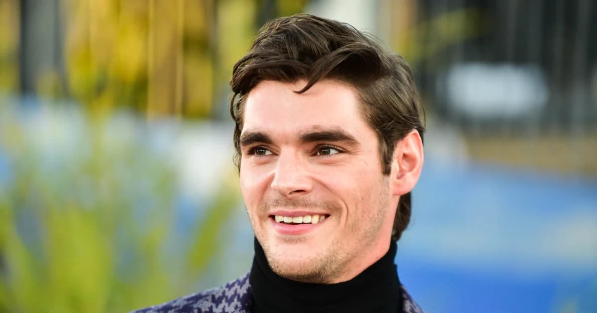 El actor RJ Mitte sonríe durante un evento al aire libre, con suéter negro de cuello alto