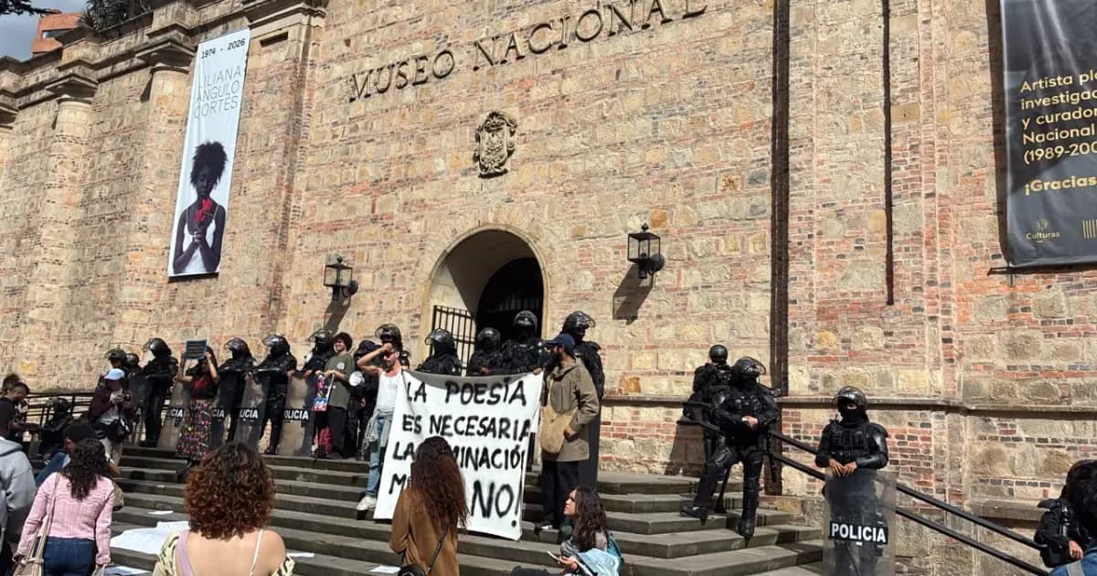 Manifestantes con una pancarta frente a la fachada del Museo Nacional, custodiada por policías antidisturbios, en Bogotá