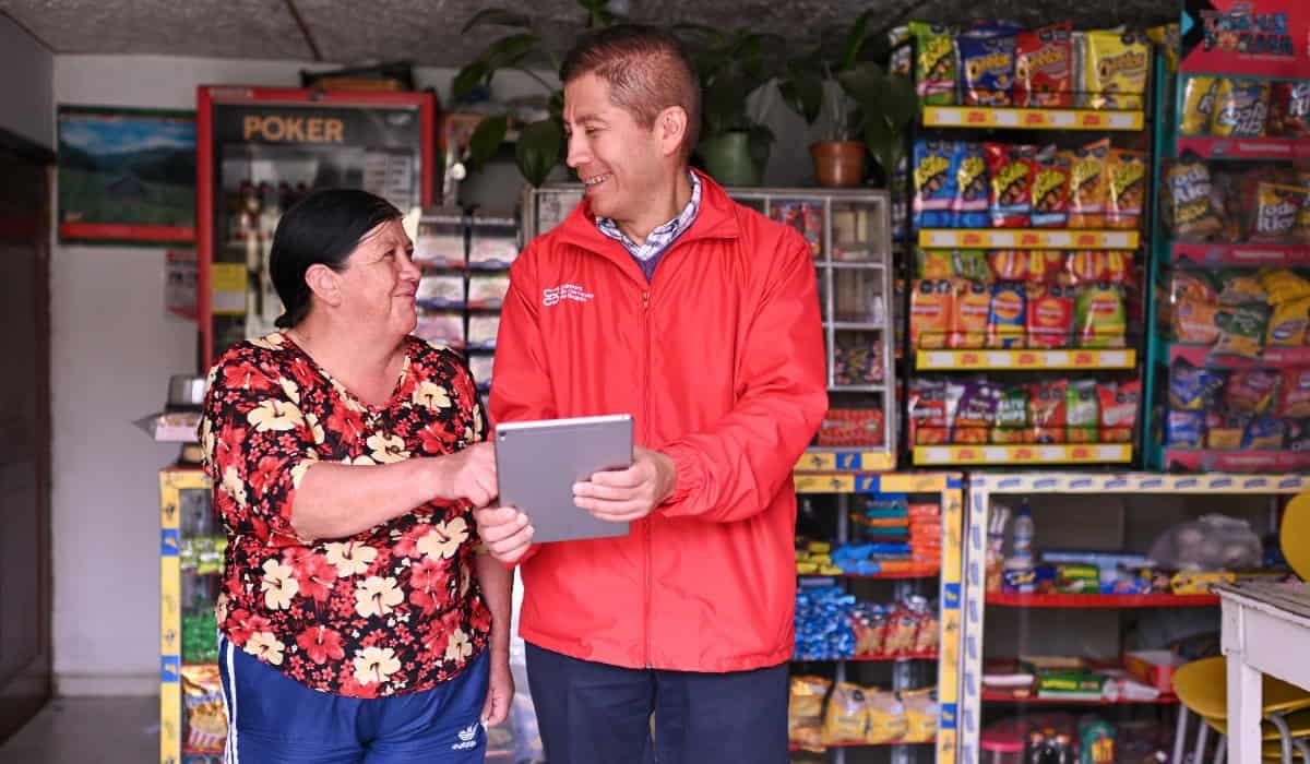 Una tendera conversa con un asesor en una tienda de barrio