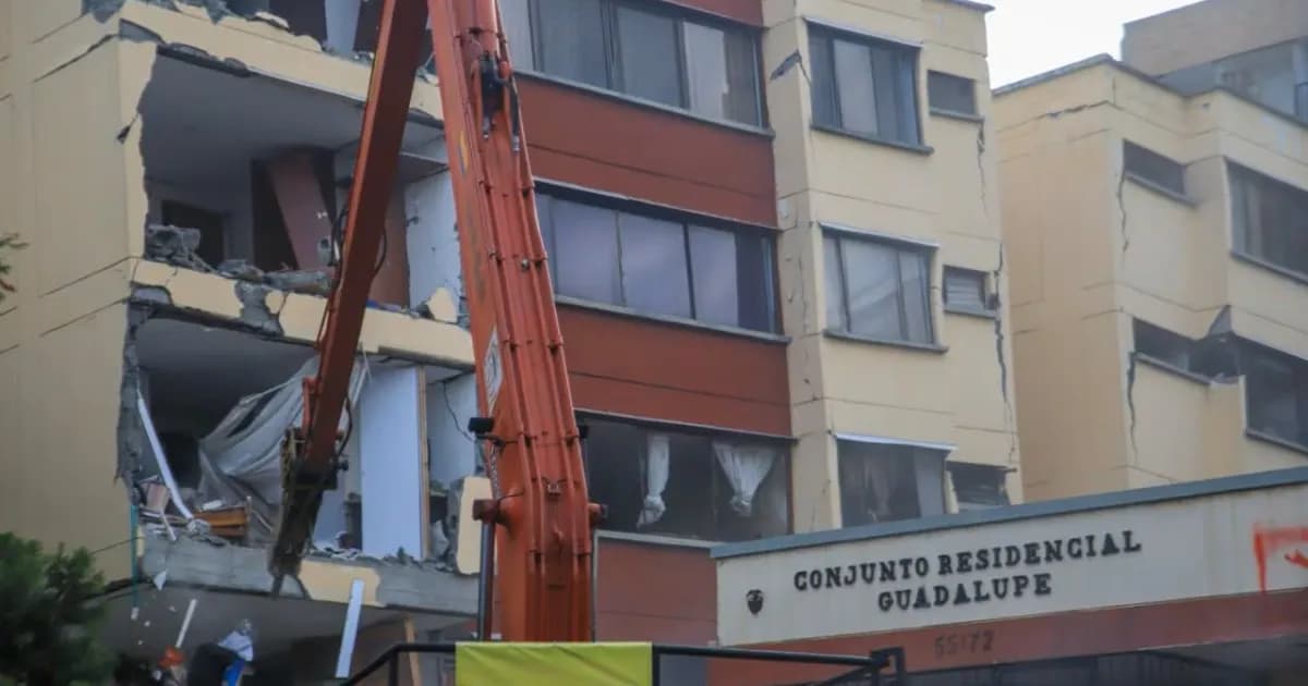 Un brazo de excavadora frente al conjunto residencial Guadalupe, con la fachada partida