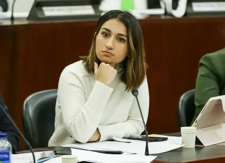Laura Sarabia, con suéter claro y la mano en el mentón, escucha sentada frente a un micrófono en una mesa con documentos durante una sesión