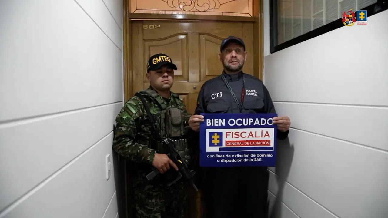 Un investigador del CTI y un soldado sostienen el letrero de bien ocupado por la Fiscalía