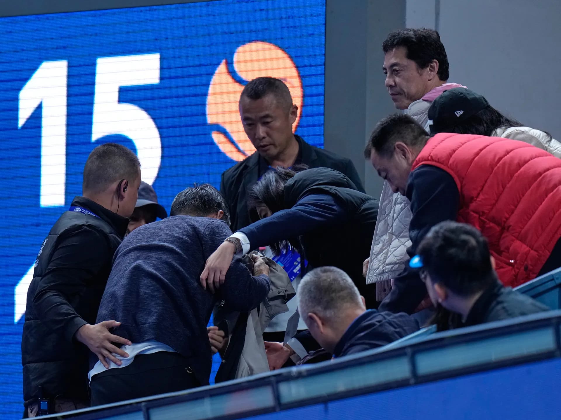 Personal del estadio ayuda a salir de la tribuna al espectador golpeado por la bola en Pekín